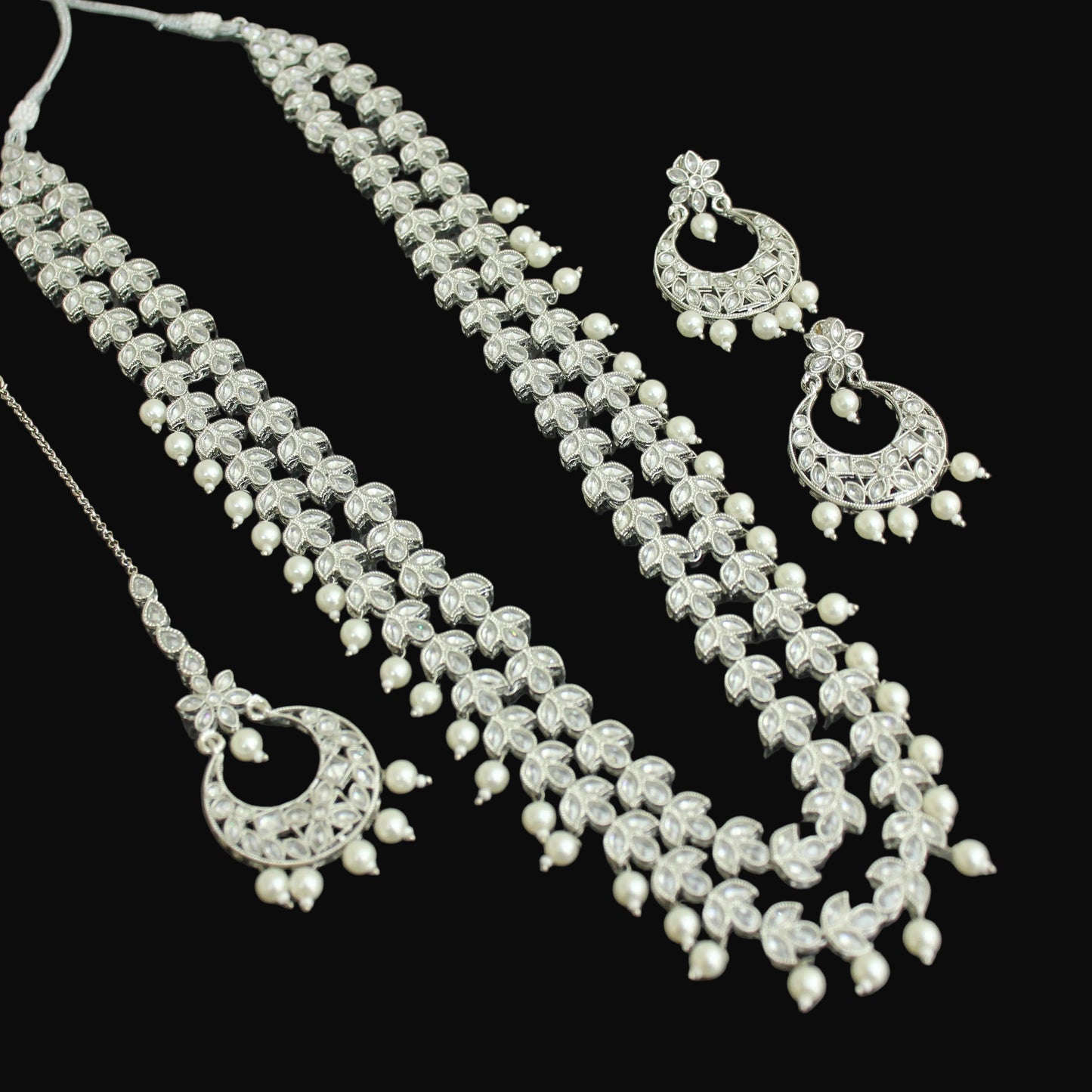 Silver necklace with matching earrings and hair accessories on a dark background