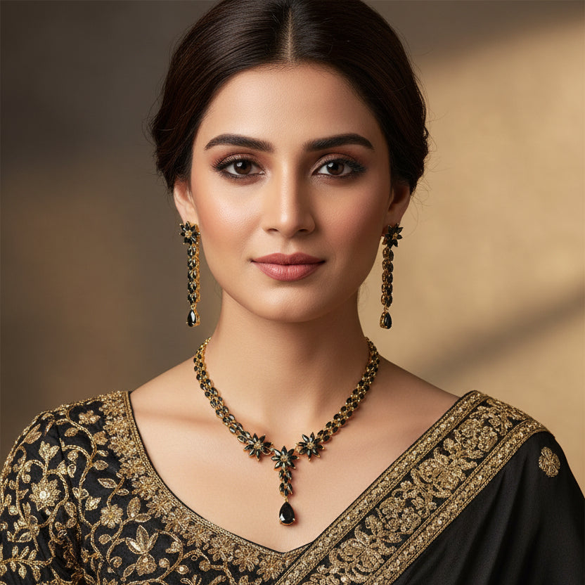 Gold necklace and earrings with black stones on a dark background