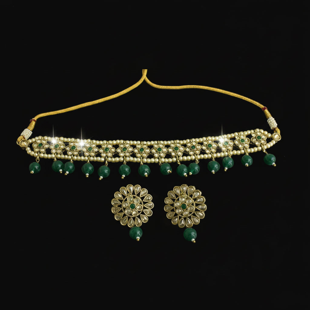 Gold necklace with green beads and matching earrings on a dark background