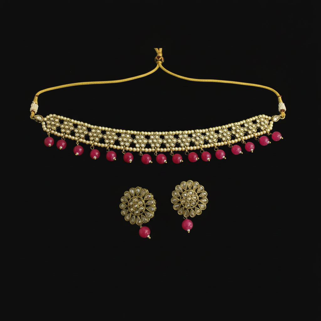 Gold necklace with red beads and matching earrings on a dark background