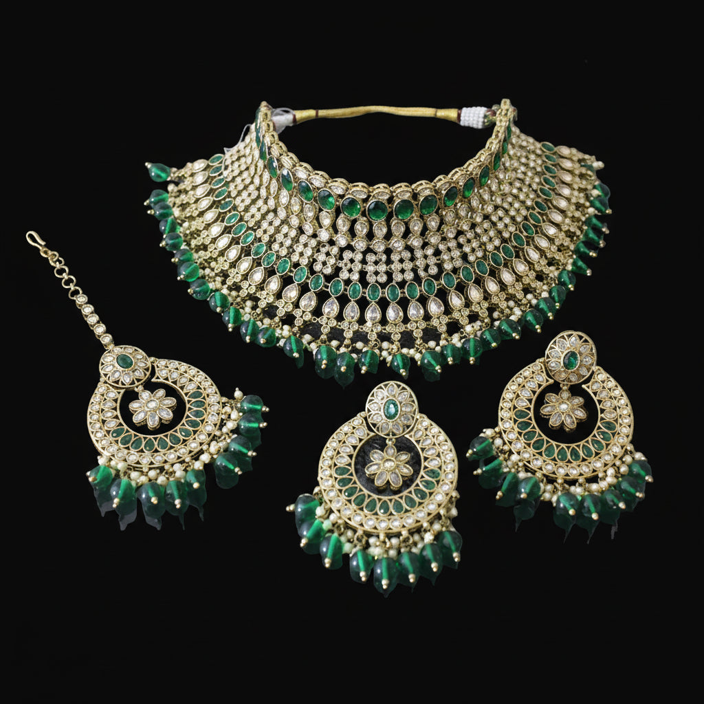 Gold and green jewelry set with necklace, earrings, and tikka on a dark background