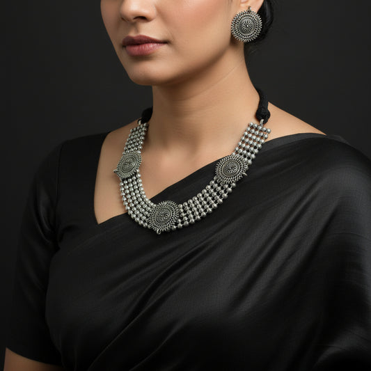 Silver necklace and earrings set on a dark background