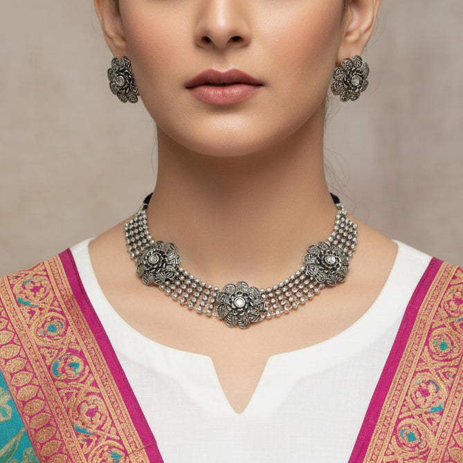 Silver necklace and earrings set with 'Saheli' branding on a dark background