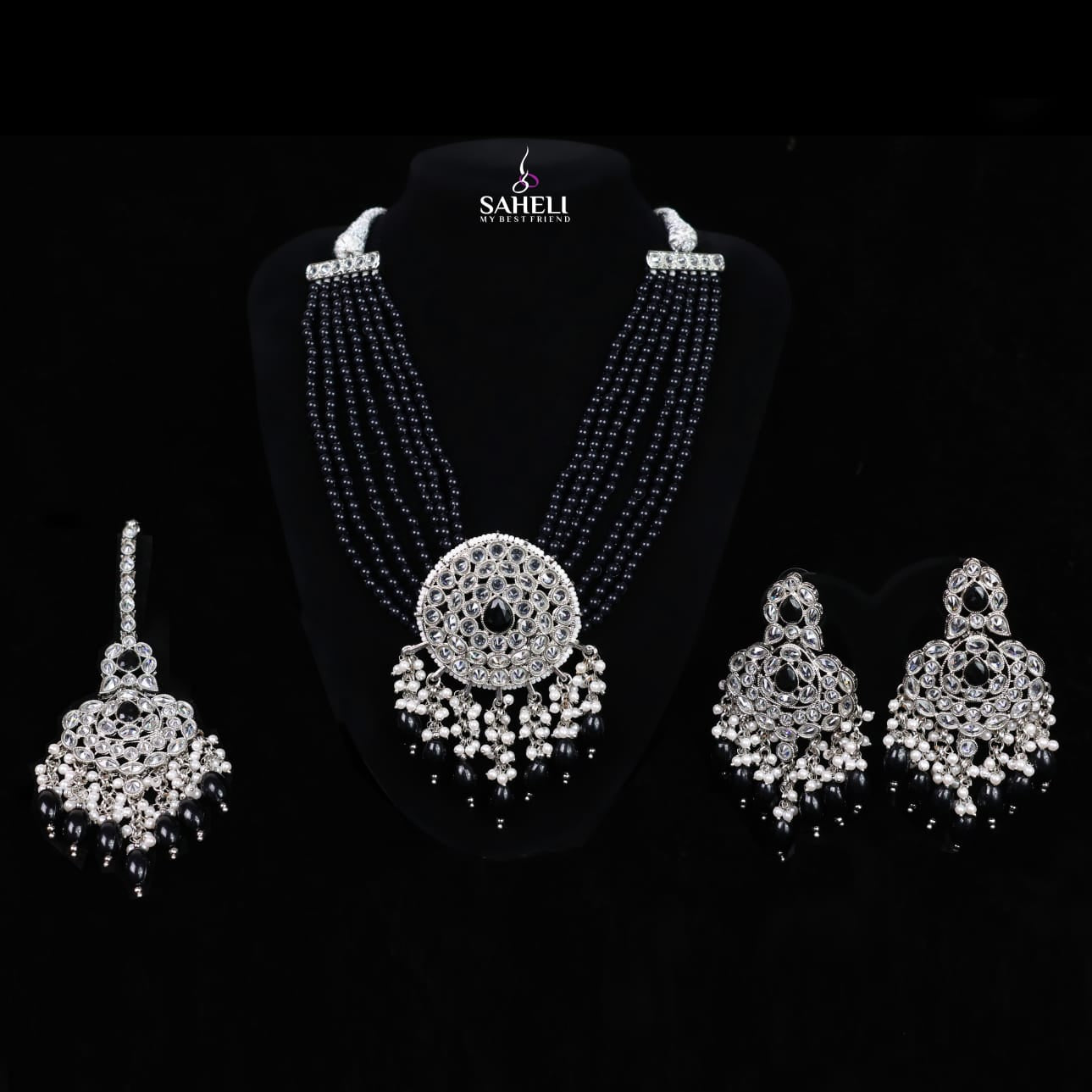 Jewelry set with necklace and earrings on a black background, featuring the brand 'Saheli'.