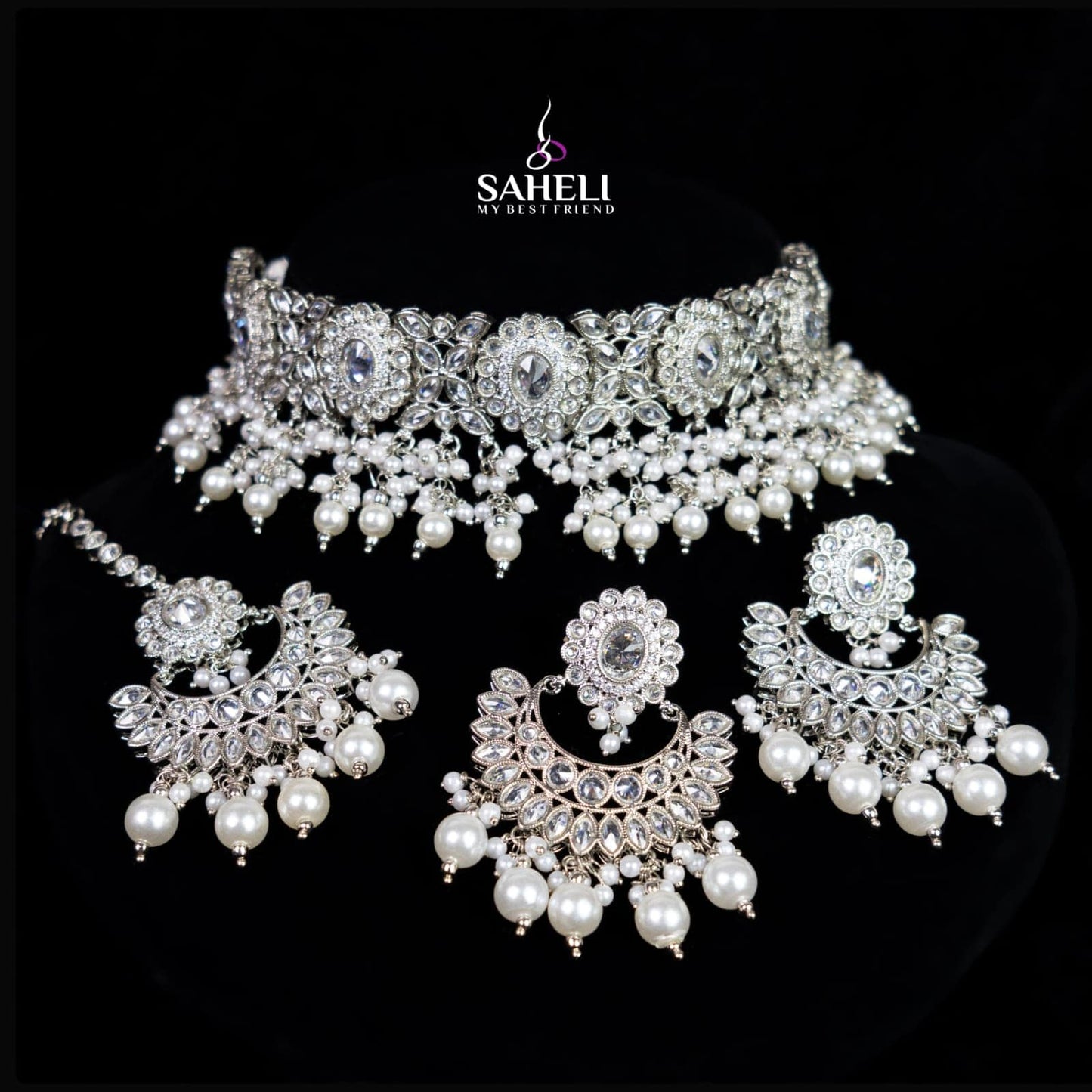 Set of silver and pearl jewelry with 'Saheli' branding on a black background