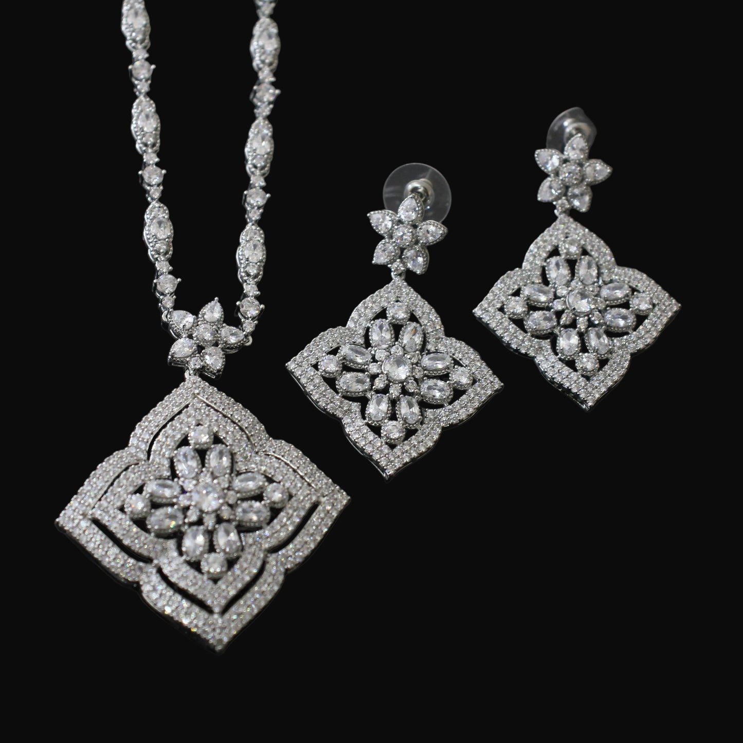 Silver necklace and earrings set on a black background