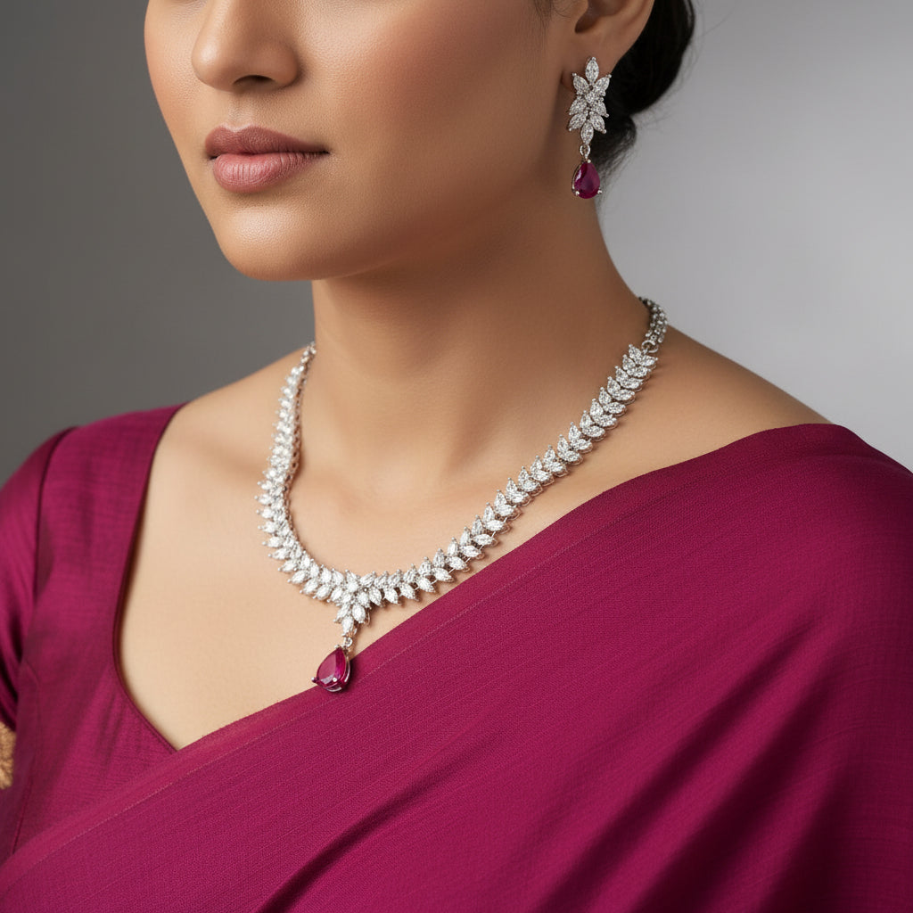 Silver necklace with pink stones and matching earrings on a dark background, branded 'Saheli'.