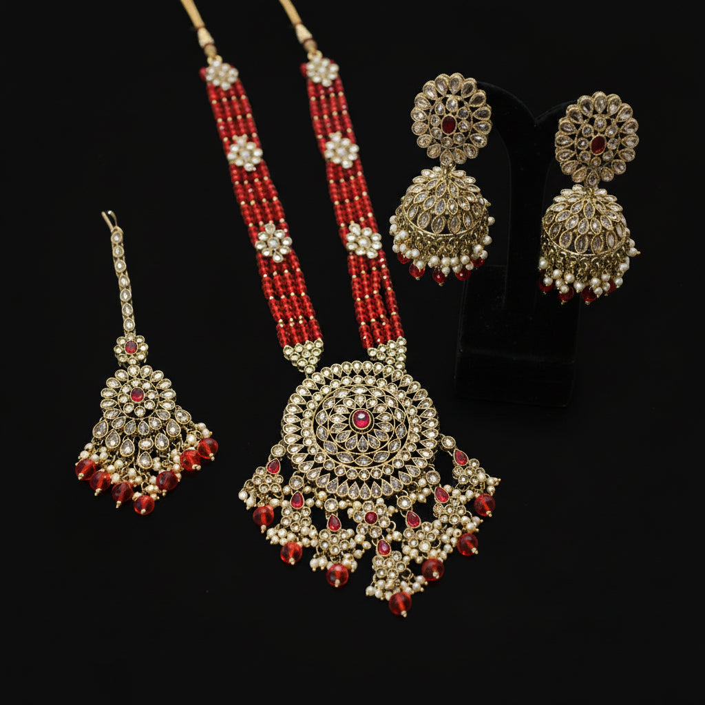 Ornate jewelry set with red and gold elements on a gray background