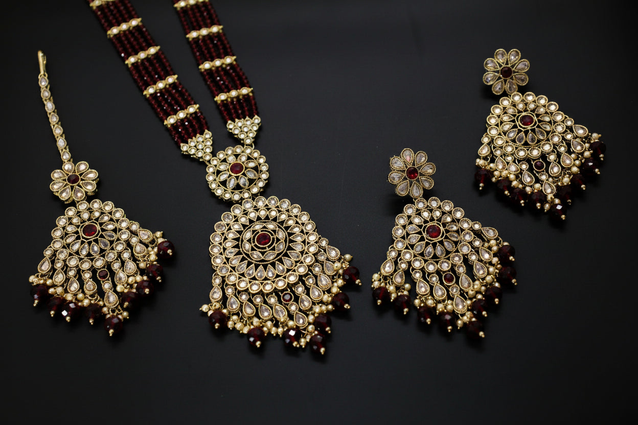 Ornate jewelry set with maroon beads on a dark background