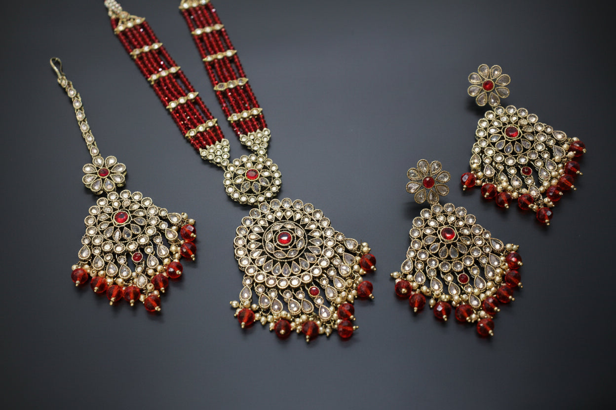 Ornate jewelry set with red and gold accents on a dark background