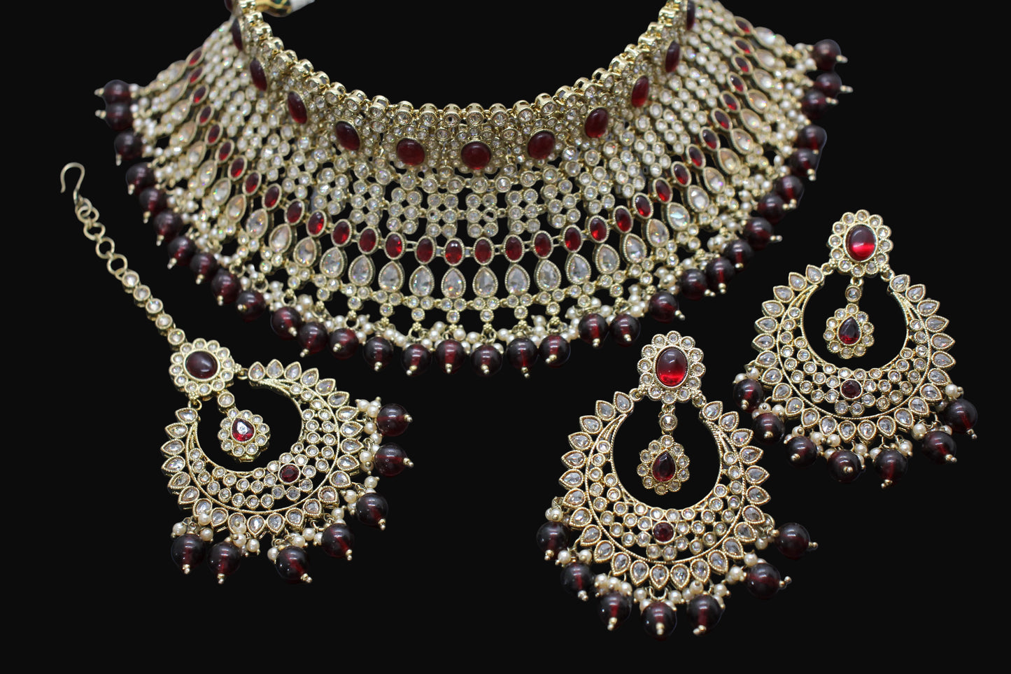 Ornate jewelry set with necklace, earrings, and tikka on a dark background