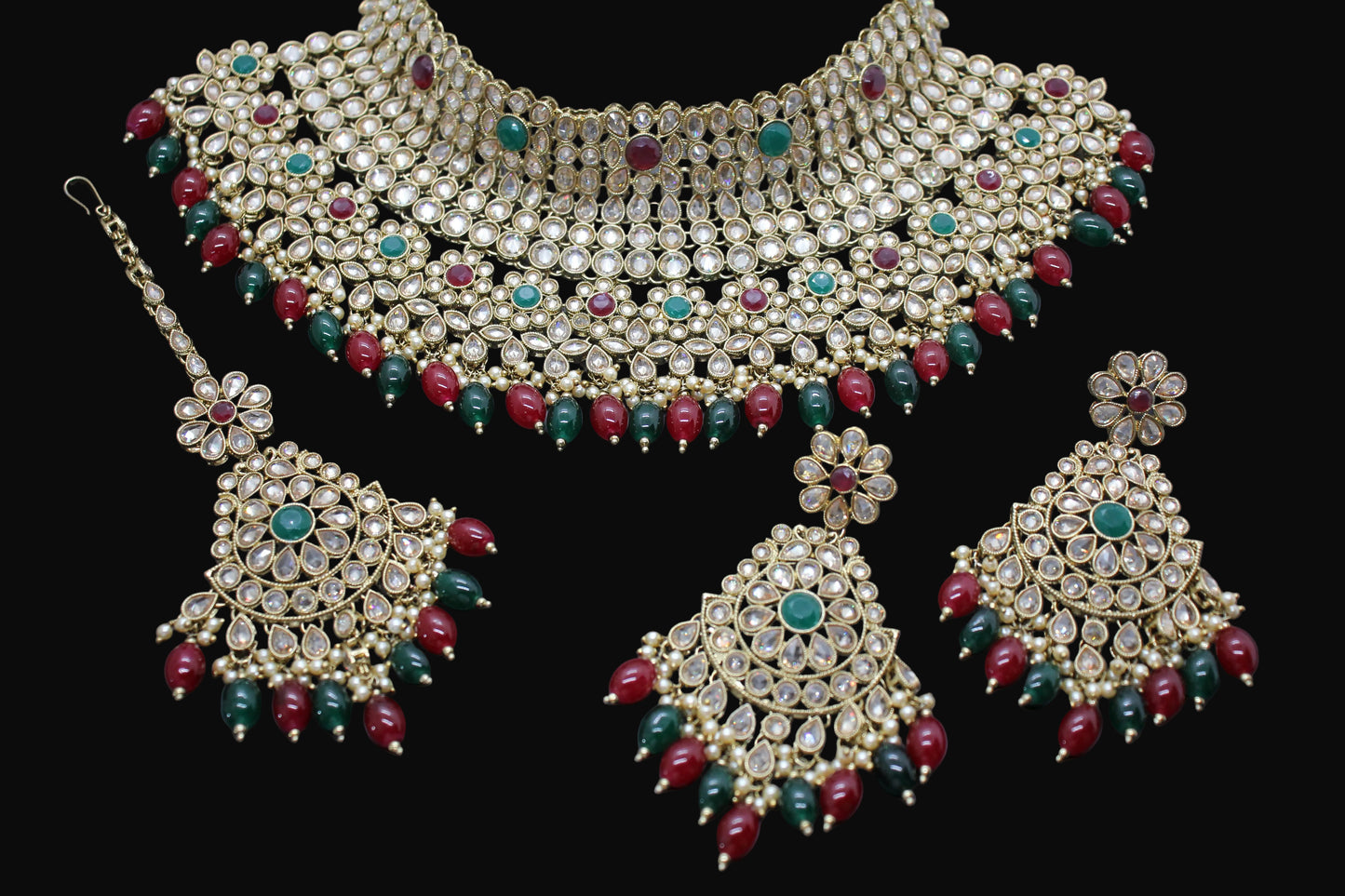 Ornate necklace set with red and green gemstones on a dark background