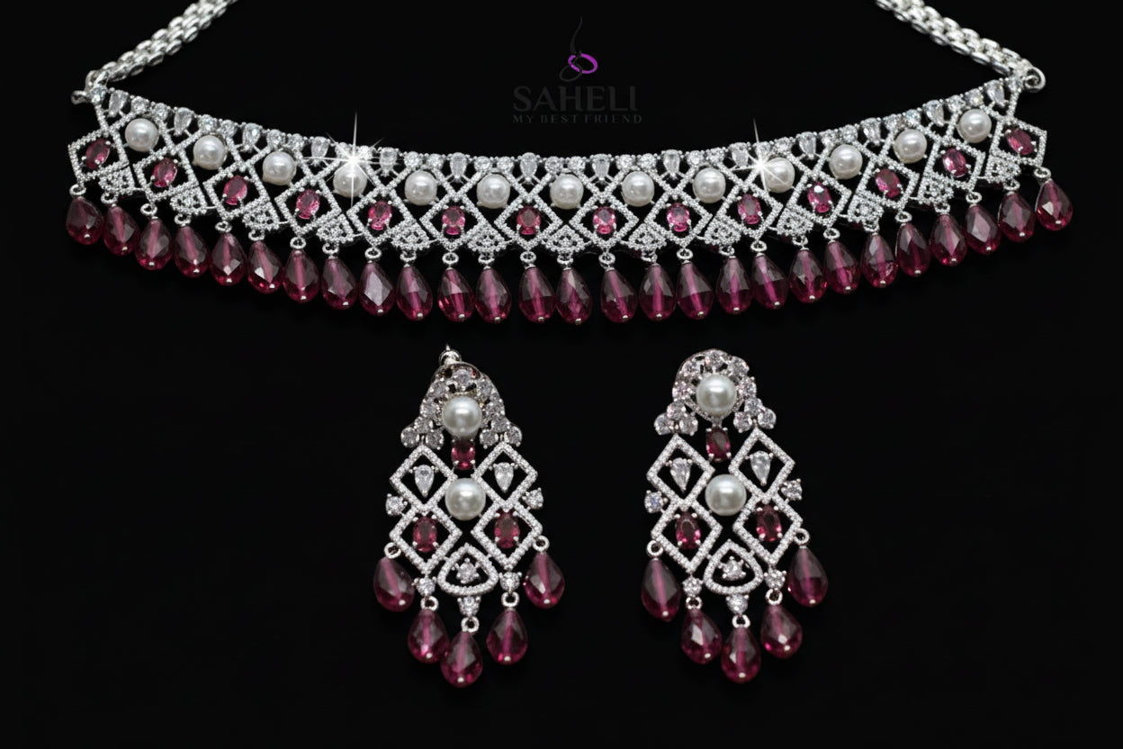 Jewelry set with necklace and earrings featuring red and silver design on a dark background, brand 'Saheli' visible.