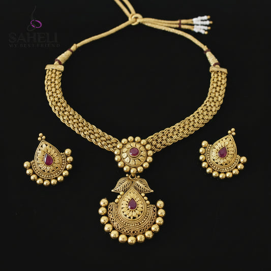 Gold necklace and earrings set with 'SAHELI' branding on a dark background