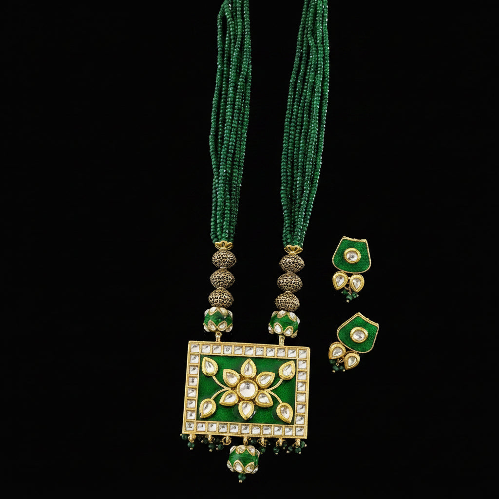 Green beaded necklace with a rectangular green and gold pendant, accompanied by matching earrings, displayed on a dark reflective surface. The brand logo 'SAHELL' is visible in the top right corner.