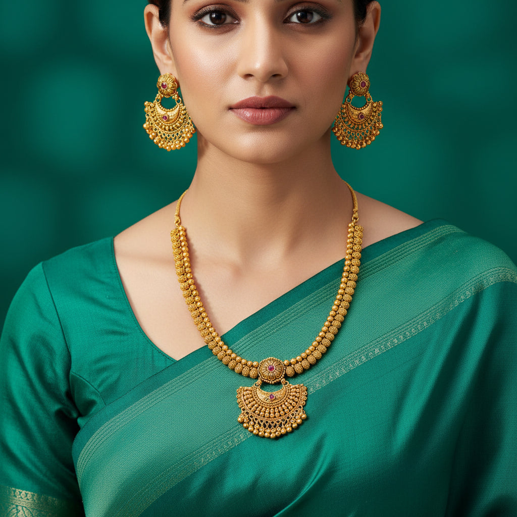 Gold necklace and earrings set on a green background