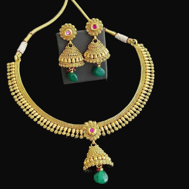Gold necklace with green gemstones and matching earrings on a black background, branded 'Saheili'.