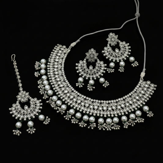 Silver jewelry set including necklace, earrings, and tikka on a dark background