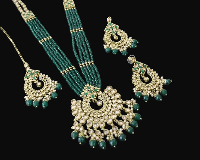 Jewelry set with necklace, earrings, and tikka on a reflective surface