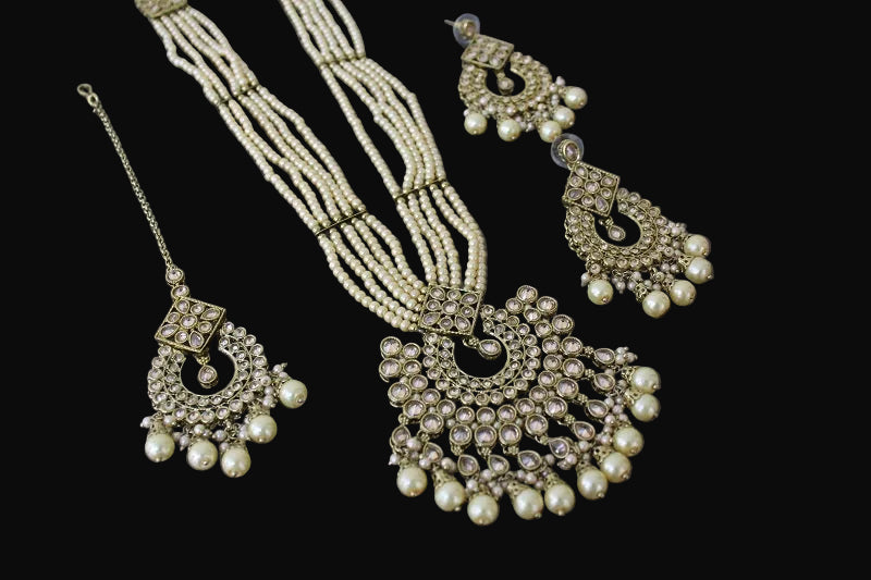 Pearl necklace and earrings set on a dark reflective surface