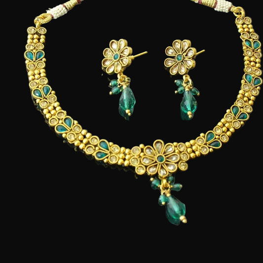 Gold necklace with green beads and matching earrings on a gray background, featuring the brand 'Saheli'.