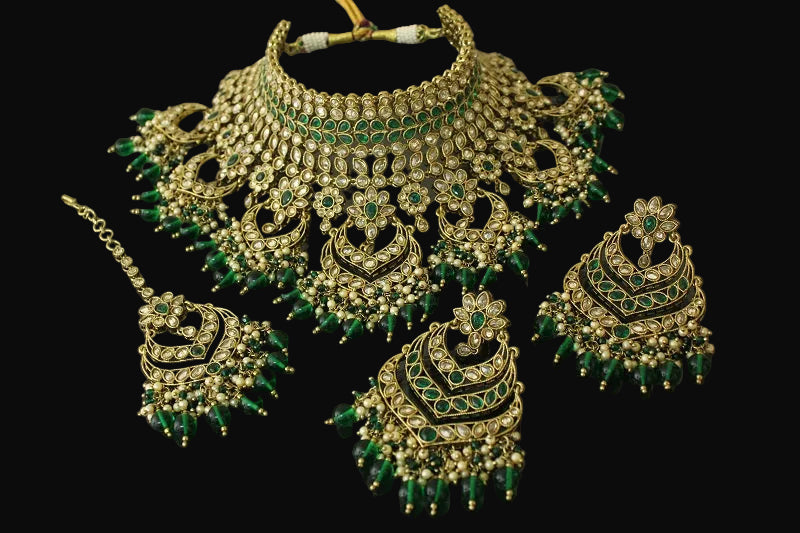 Gold and green jewelry set on a dark background
