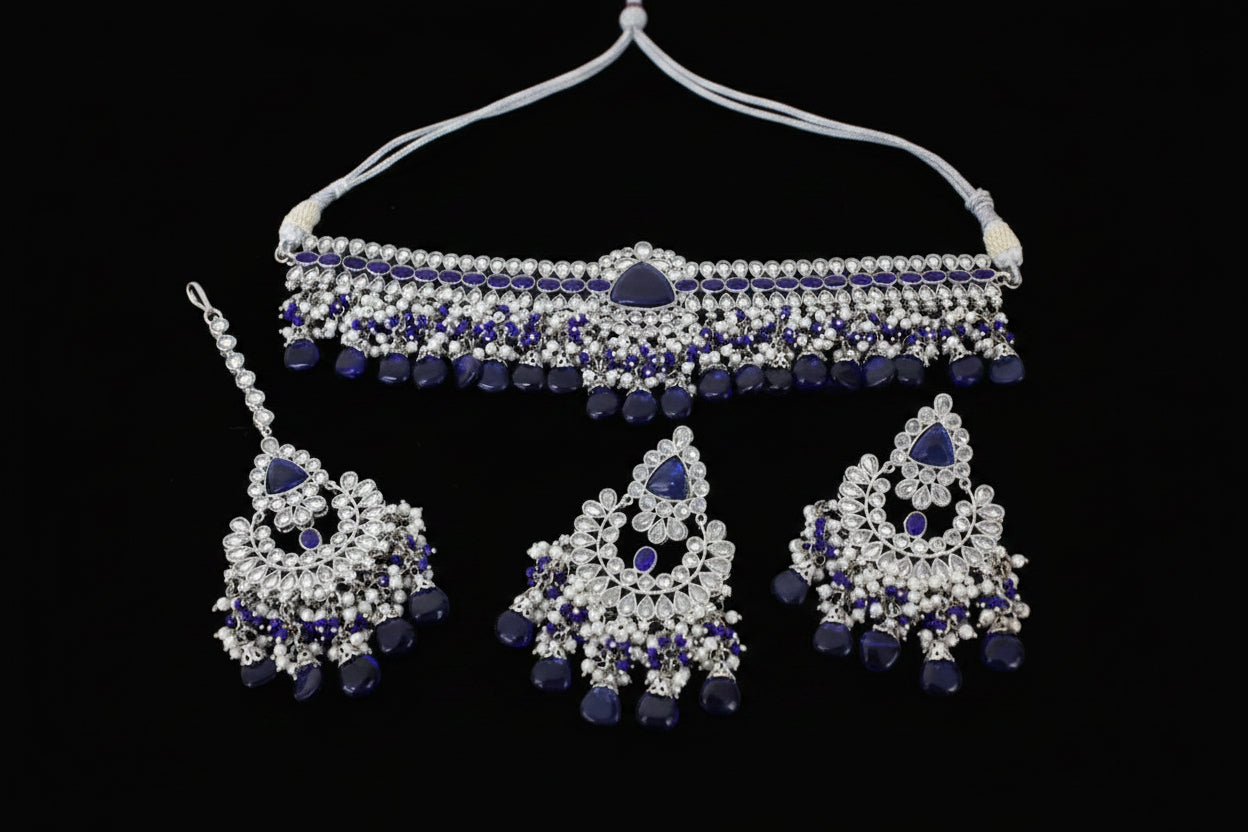 Jewelry set with necklace, earrings, and hair accessories featuring blue and silver stones on a dark background.