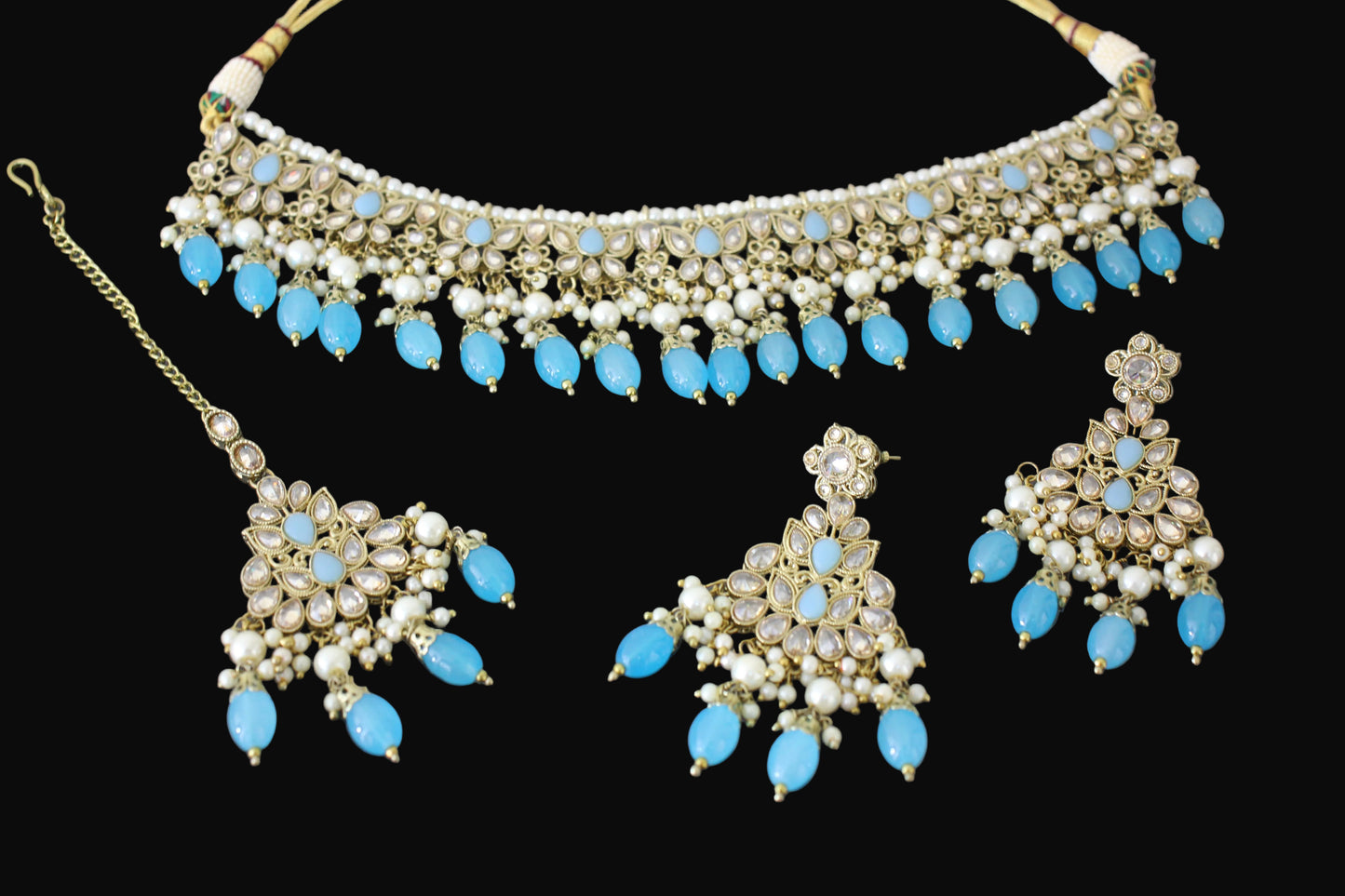 Jewelry set with necklace, earrings, and tikka on a dark background