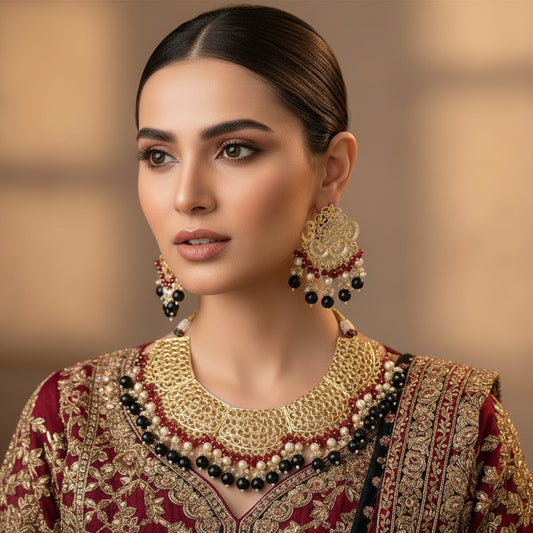 Ornate necklace and earrings set with red, black, and gold colors on a dark background