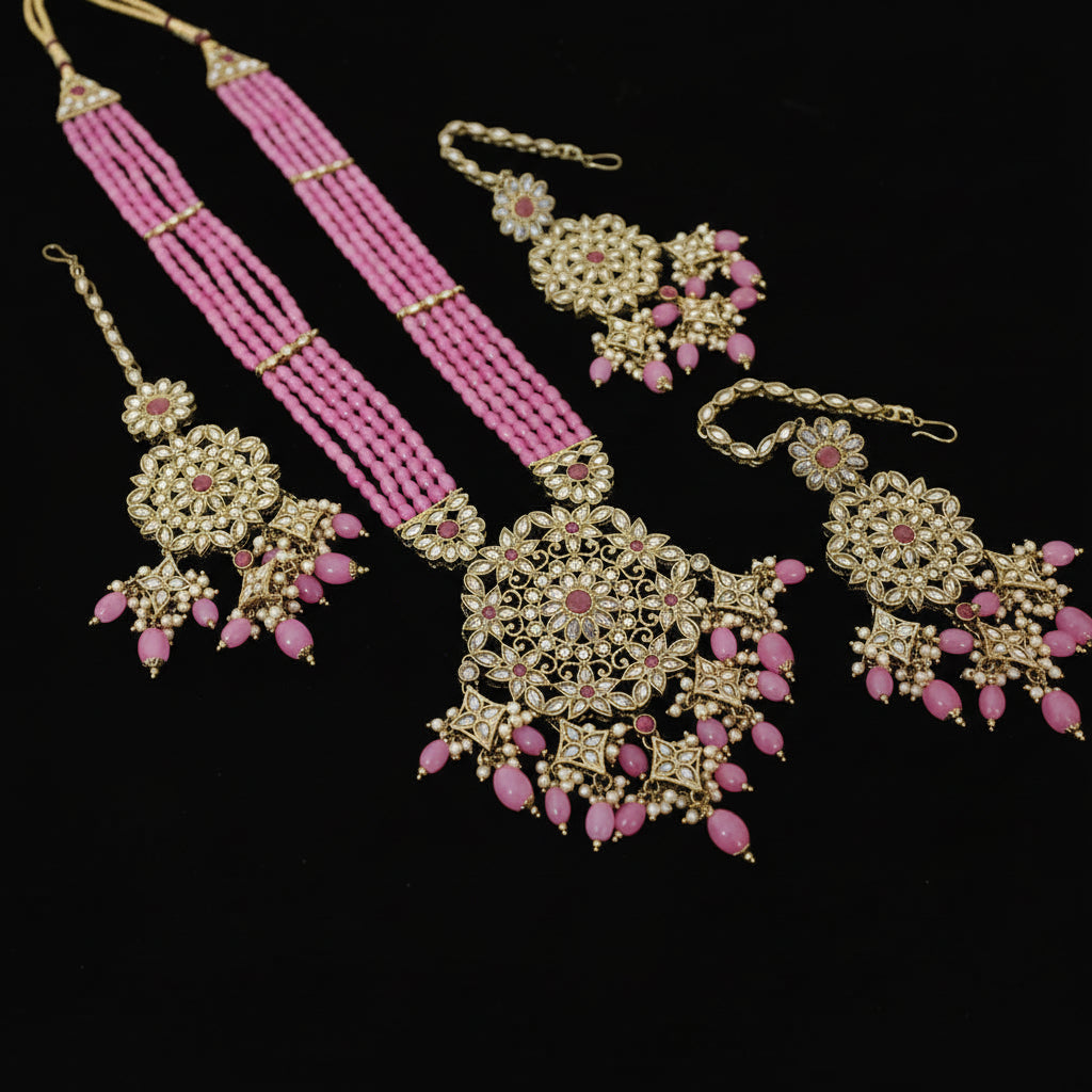 Ornate jewelry set with pink beads on a reflective surface