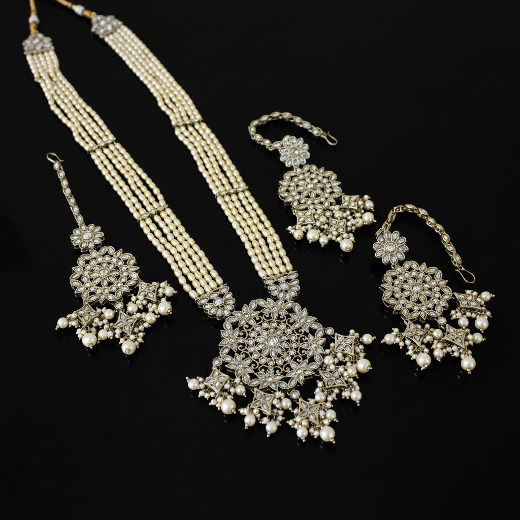 Silver jewelry set with necklaces and earrings on a dark background