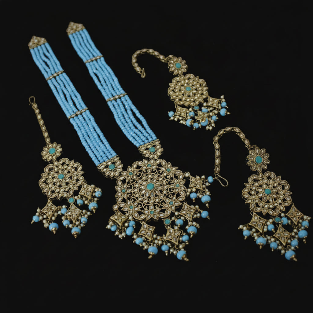 Ornate jewelry set with blue beads on a reflective surface