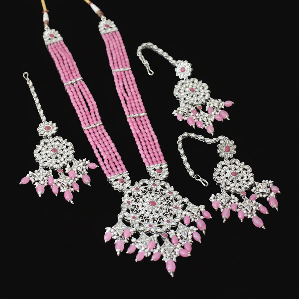 Jewelry set with pink beads and silver accents on a dark surface