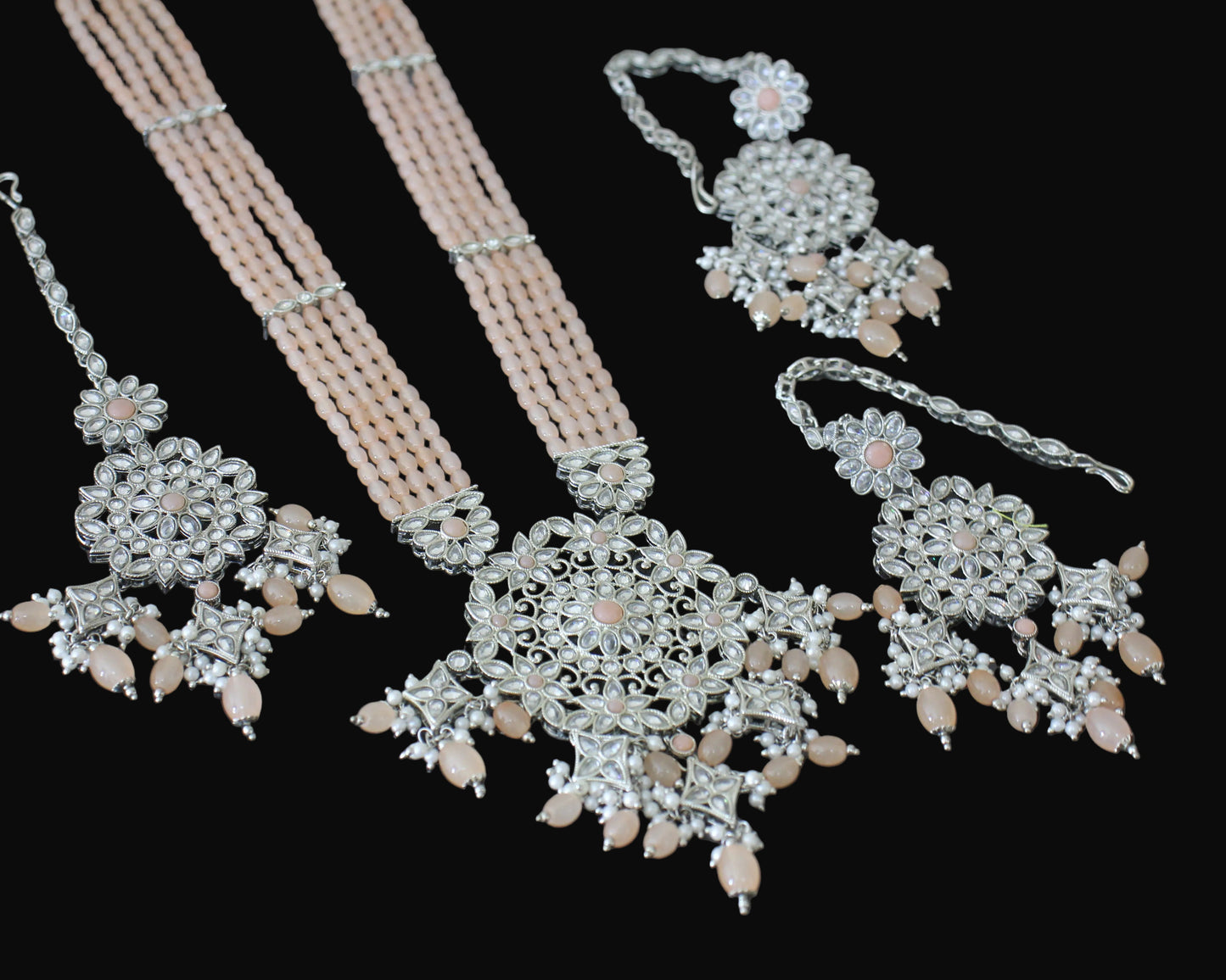 Silver jewelry set with necklace, earrings, and hair accessories on a dark background