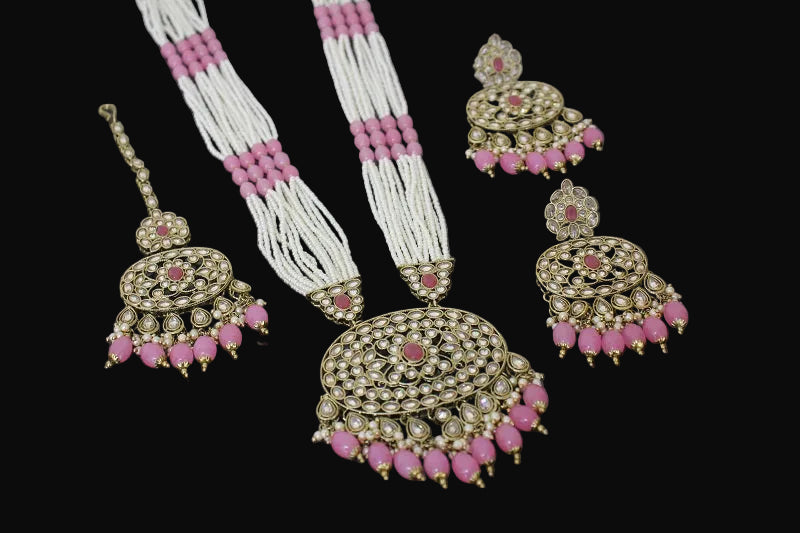 Set of traditional jewelry with pink and white beads on a dark background