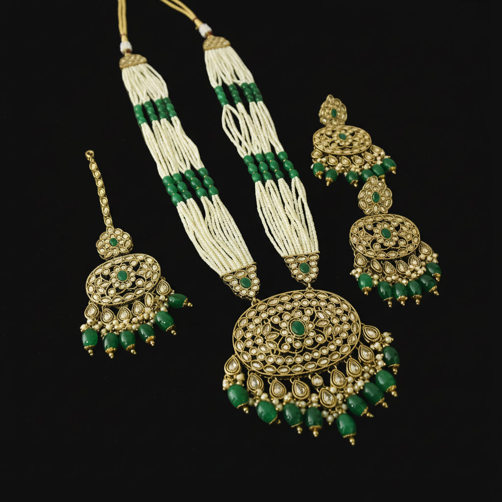 Gold and green jewelry set on a reflective surface