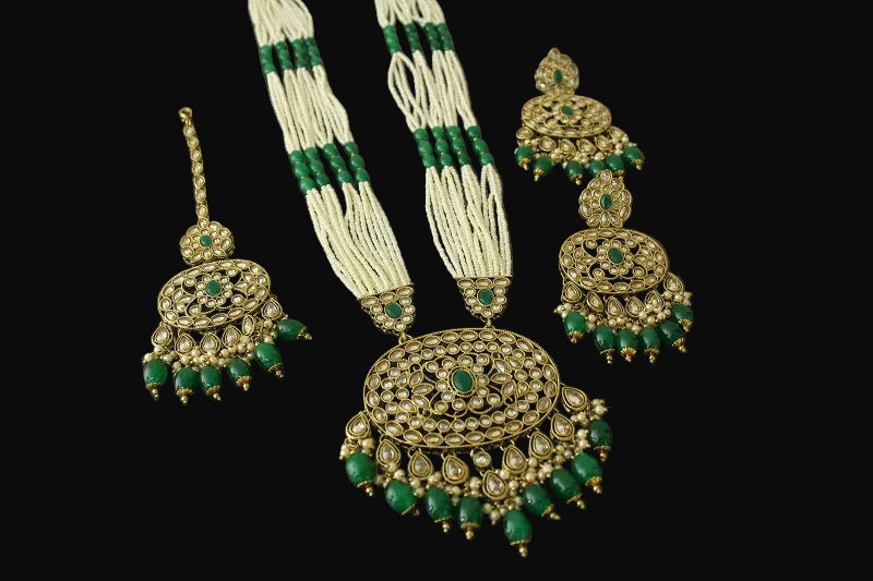 Gold and green jewelry set on a reflective surface