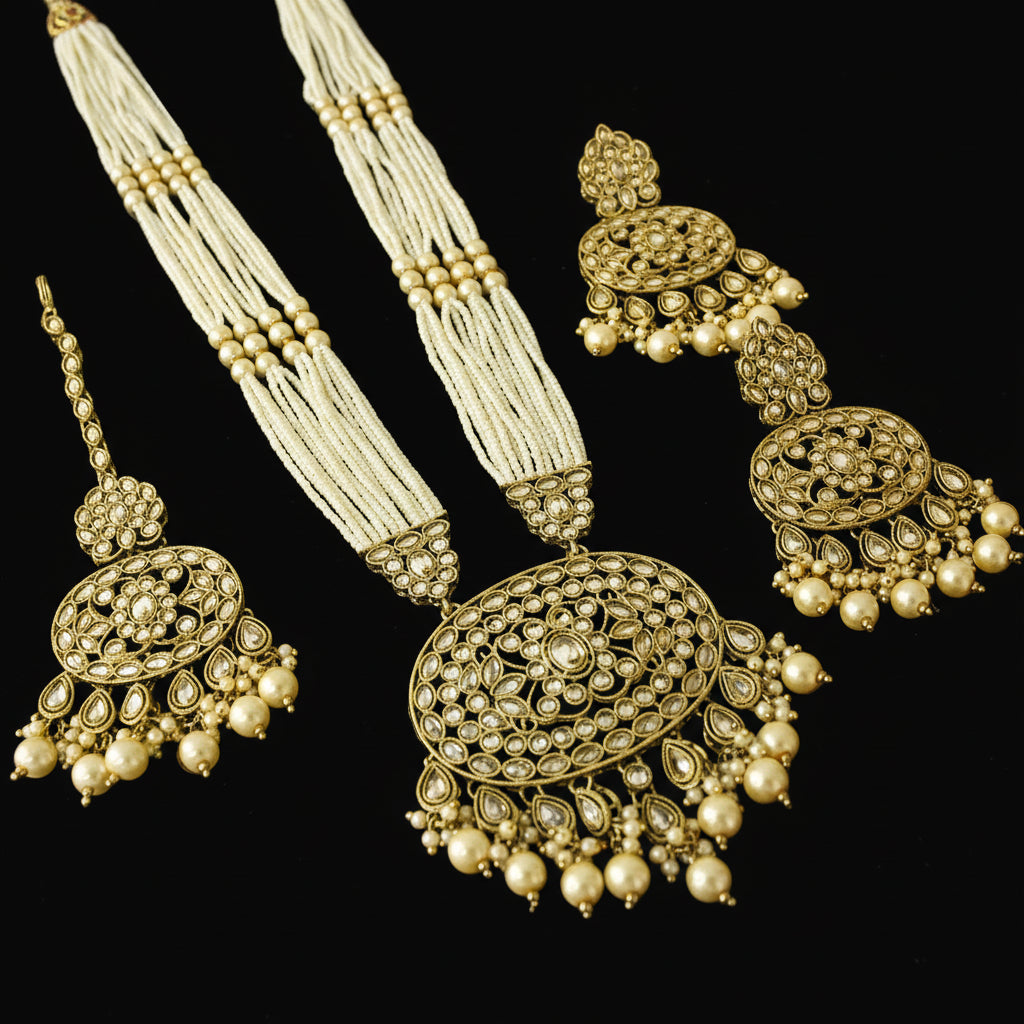 Ornate gold and pearl necklace with matching earrings on a reflective black surface