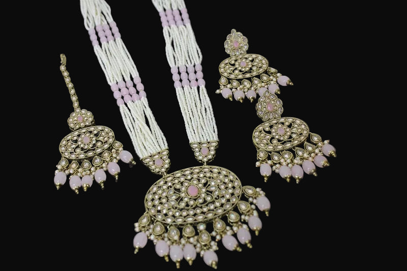 Set of traditional jewelry including earrings and a necklace on a reflective surface.