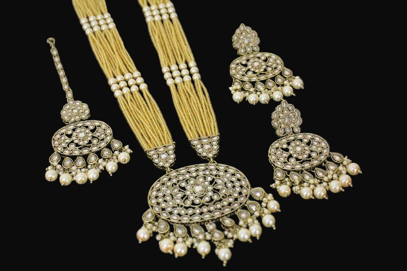 Ornate jewelry set with earrings and a necklace on a dark background