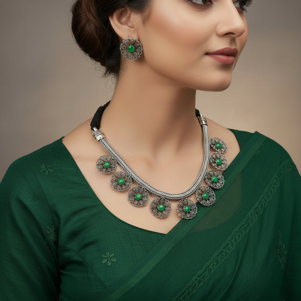 Necklace with floral silver pendants and green stones on a gray background