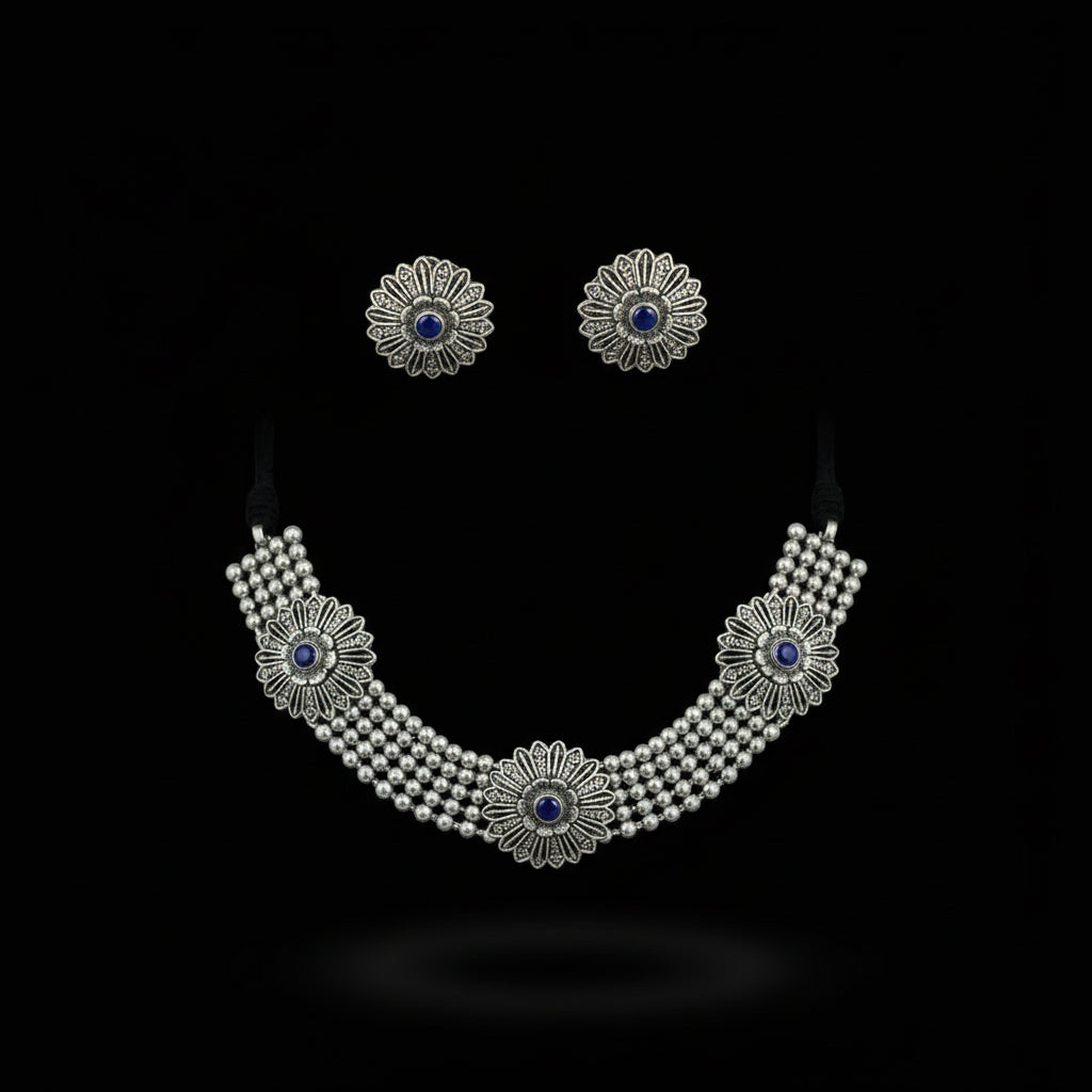 Silver necklace with floral designs and blue stones on a dark background