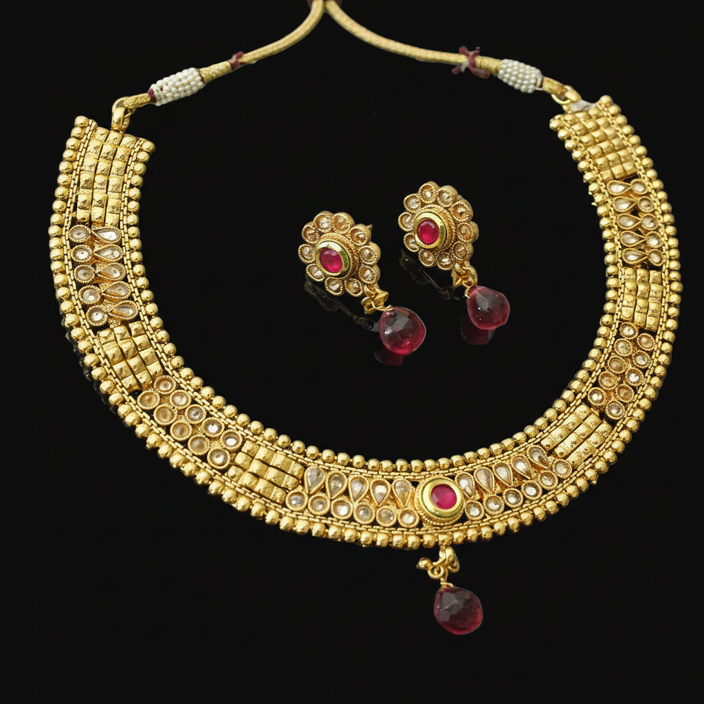Gold necklace and earrings with red stones on a dark background, branded 'Saheli'.