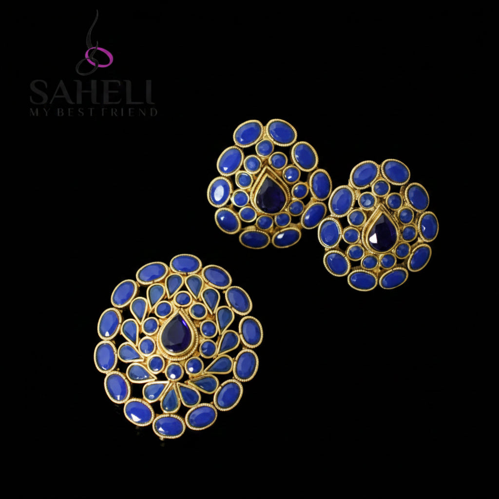 Blue and gold earrings on a dark background with 'Saheli' branding.