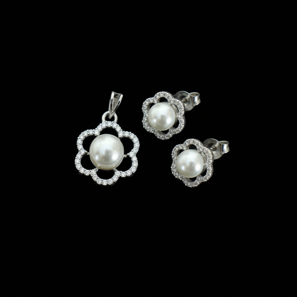 Pearl earrings with silver floral designs on a dark background, branded 'Saheli'.