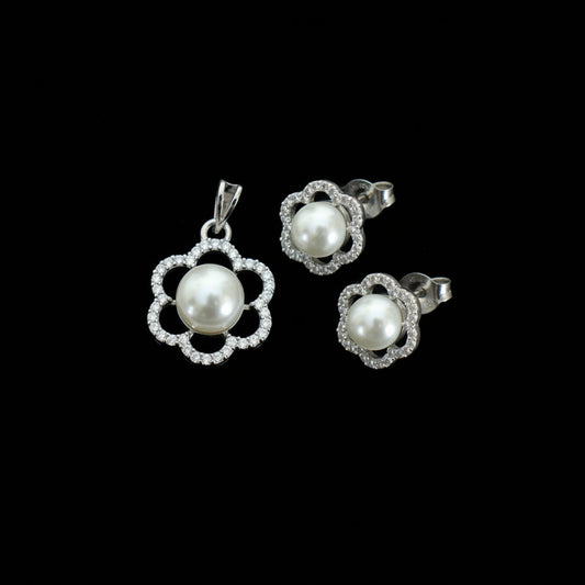 Pearl earrings with silver floral designs on a dark background, branded 'Saheli'.