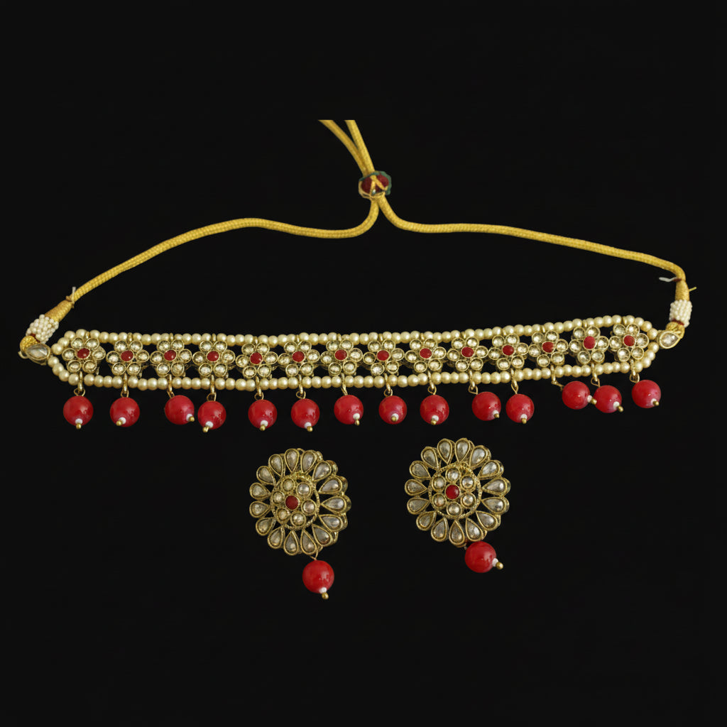 Gold necklace with red stones and matching earrings on a dark background
