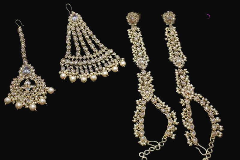 Set of gold jewelry including earrings and a necklace on a dark background with 'SAHeli' branding.