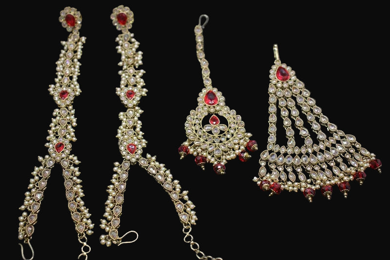 Ornate jewelry set with red stones on a dark background, featuring the brand 'Saheli'.