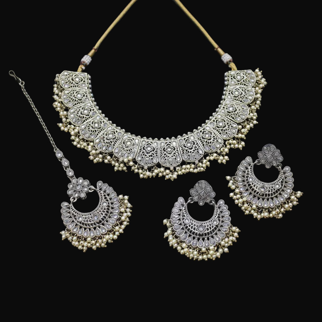 Ornate necklace and earrings set on a dark background